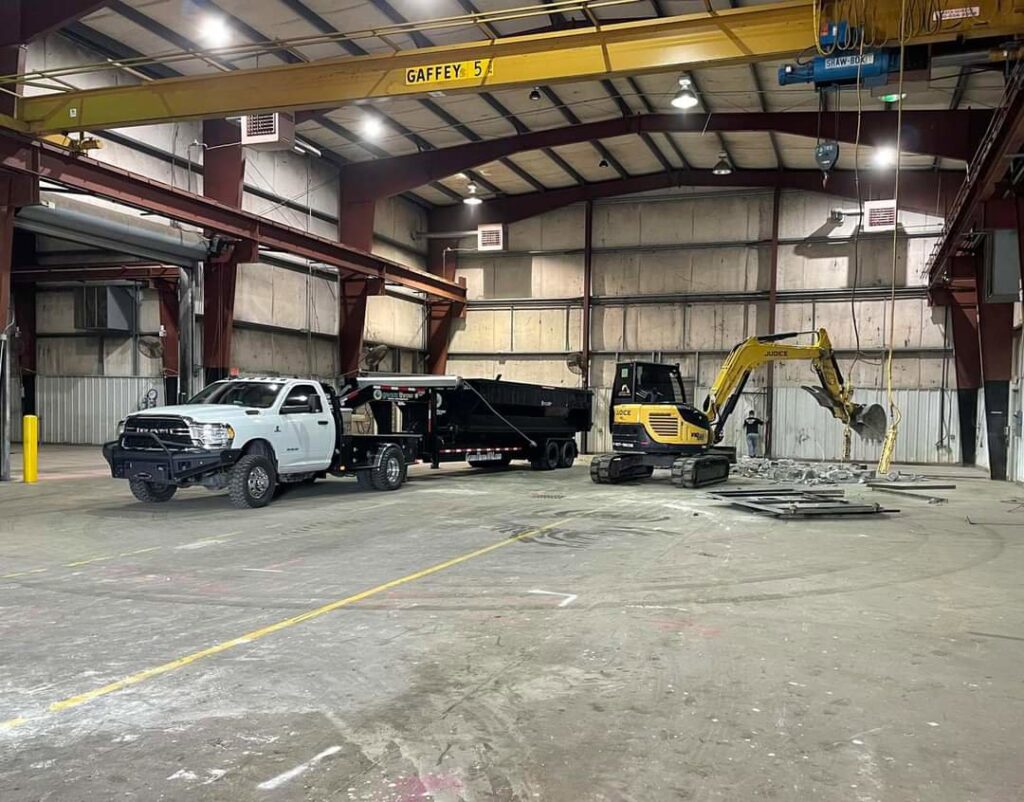 An excavator from Judice Dirt & Demolition moving metal debris inside a warehouse during an interior demolition project in Lafayette, LA.