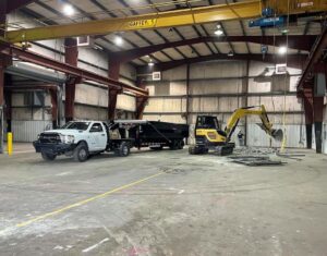 An excavator from Judice Dirt & Demolition moving metal debris inside a warehouse during an interior demolition project in Lafayette, LA.