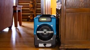 A blue industrial air mover drying a wooden floor during water damage restoration by Pure Restore in Northglenn, CO.