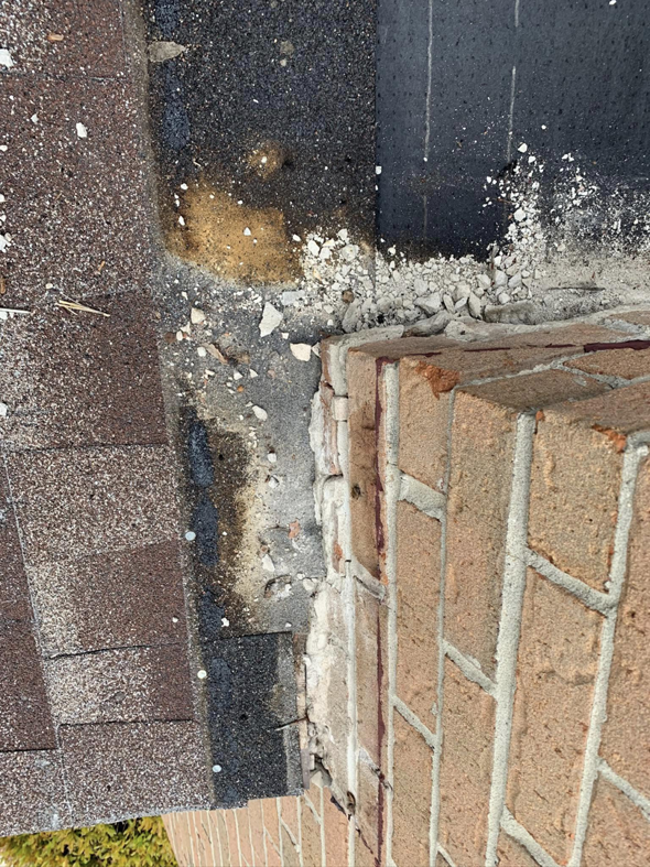 Water damage and crumbling material around a chimney base on a roof, repaired by QUICK STOP HOME Repair in Parker, CO.