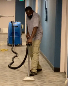 A worker performing water damage carpet extraction with a professional machine for Renue Systems Of Oahu in Honolulu, HI