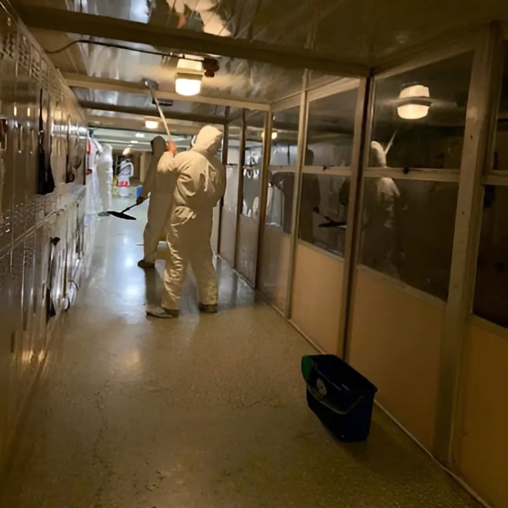 Workers in hazmat suits cleaning and extracting water from a damaged hallway floor for Superior Contract Cleaning in Lafayette, LA.