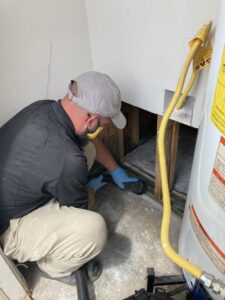 A PuroClean technician performing water damage cleanup near a water heater in Northport, AL.