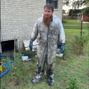 A water damage cleanup worker in a heavily soiled protective suit after a job by 13:12 Cleaning & Restoration, LLC in Bessemer, AL