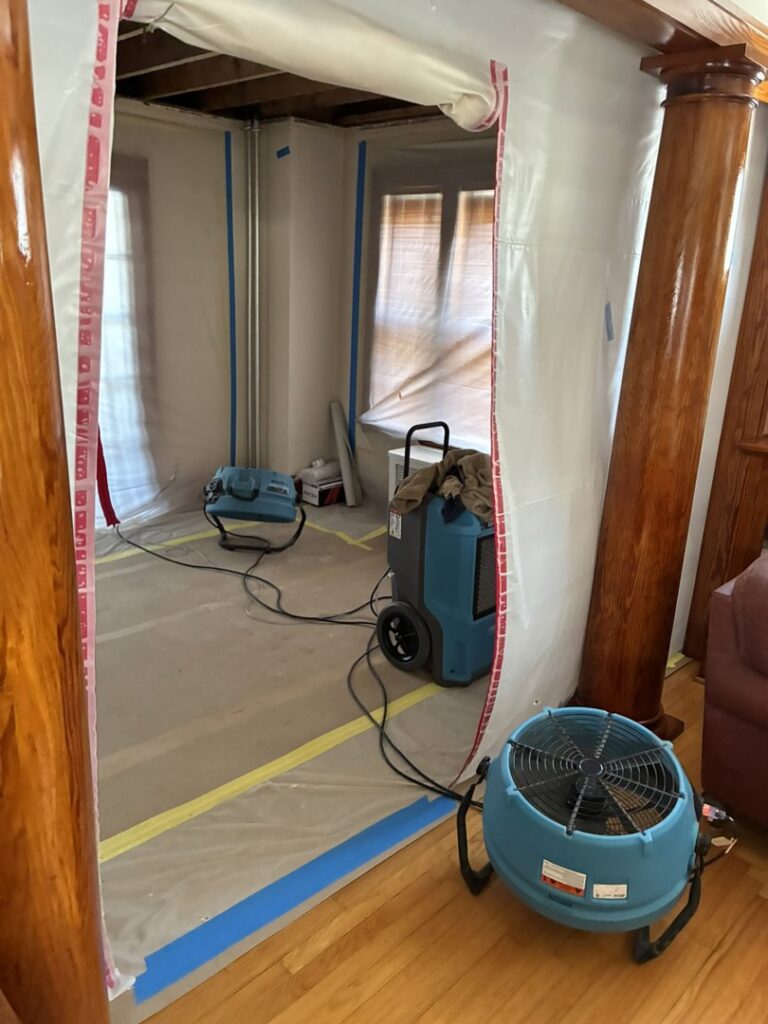A room with plastic containment and drying equipment for water damage restoration by CleanBright Surface Restoration in Latham, NY.