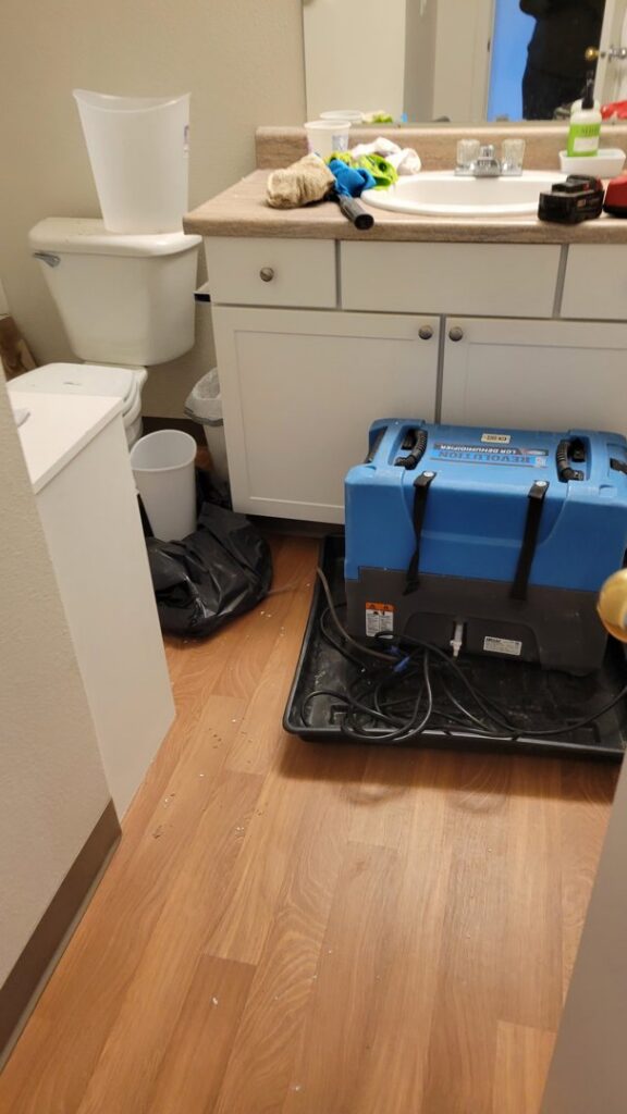 A large blue water damage dehumidifier operating in a bathroom during restoration by Robinson Restoration in Vancouver, WA