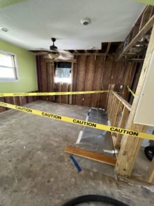 A room undergoing demolition and remediation after severe water damage, with caution tape, by Elements of Restoration in Denver, CO.