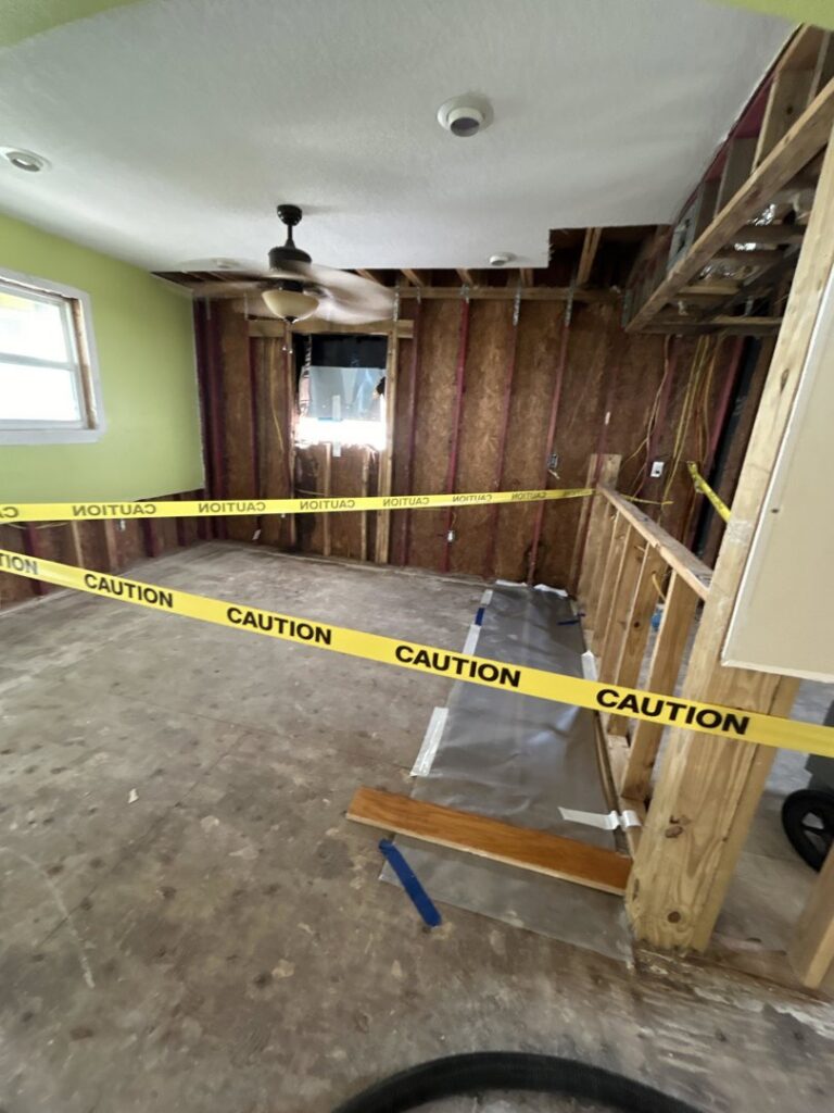 A room undergoing demolition and remediation after severe water damage, with caution tape, by Elements of Restoration in Denver, CO.
