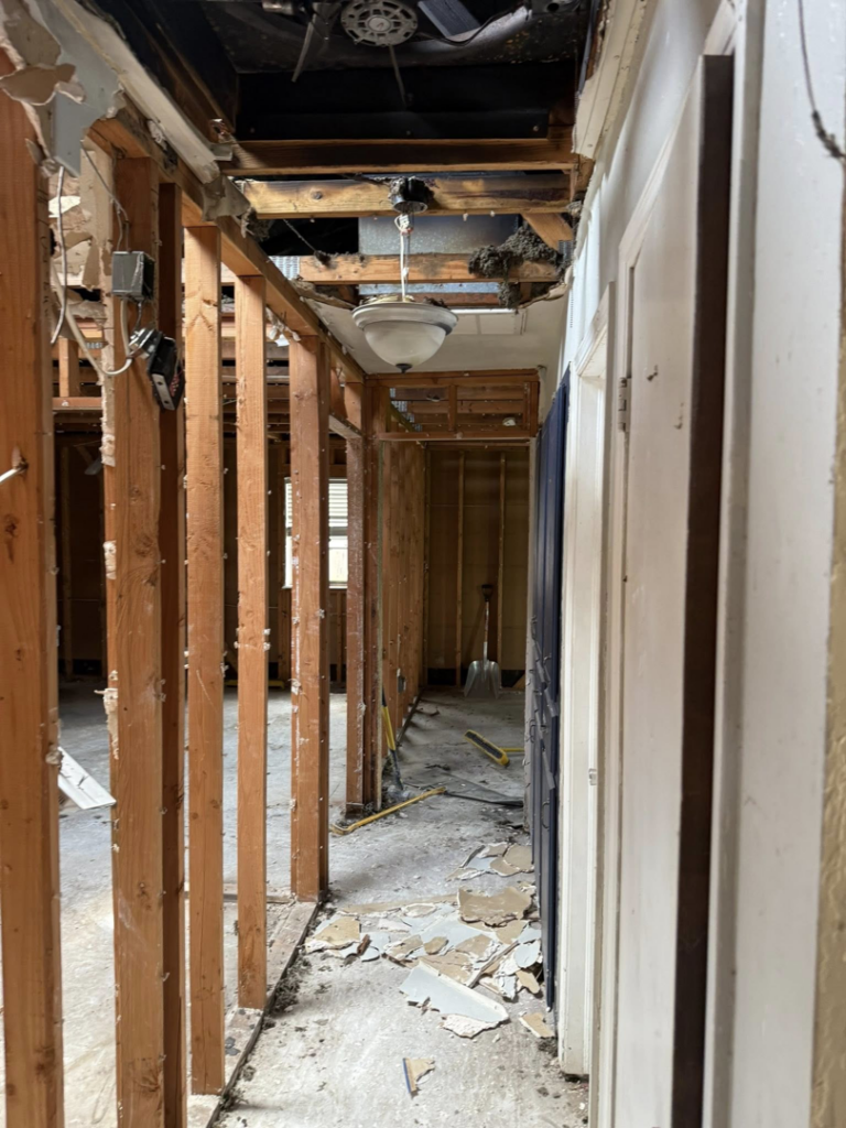 Interior hallway after demolition for water damage, showing exposed studs and joists by Express Restoration in Edmond, OK.
