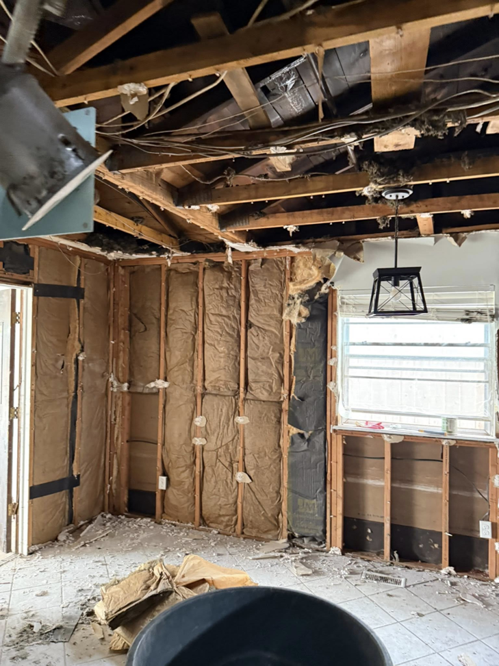 Room interior after water damage demolition, with exposed studs and insulation, handled by Express Restoration in Edmond, OK.