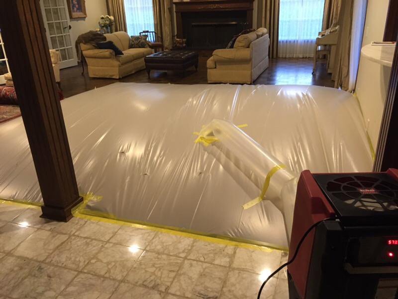 A large plastic containment system and drying equipment set up in a living room for water damage restoration by Restoration 1 of OKC in Yukon, OK.