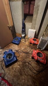 Water damage drying equipment and a wet vacuum in a basement undergoing restoration by Water Damage, Inc. in Denver, CO.