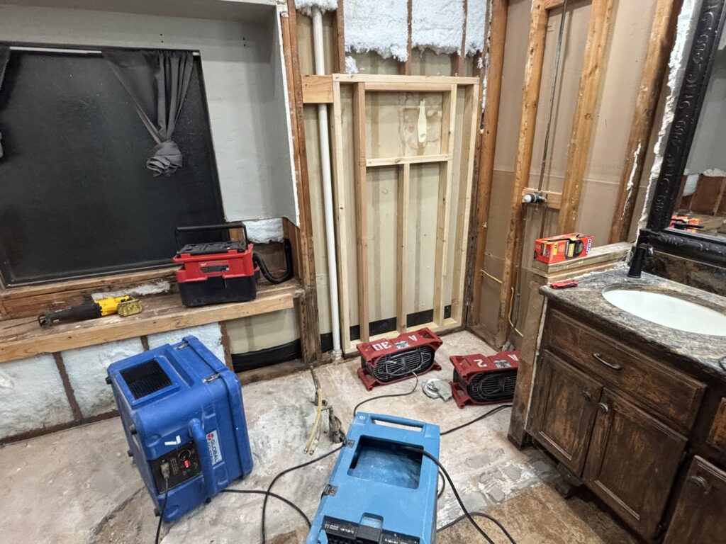 Air movers and dehumidifiers drying a water-damaged bathroom during remediation by OKSR - Property Restoration Services in Oklahoma City, OK.