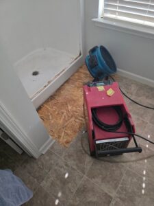 Water damage drying equipment, including a dehumidifier and air mover, in a bathroom by Restoration Specialist in O Fallon, MO.