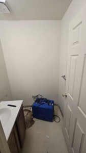 Water damage drying equipment in a small bathroom, indicating water mitigation services by Simon Says Do It, LLC in New Castle, DE.