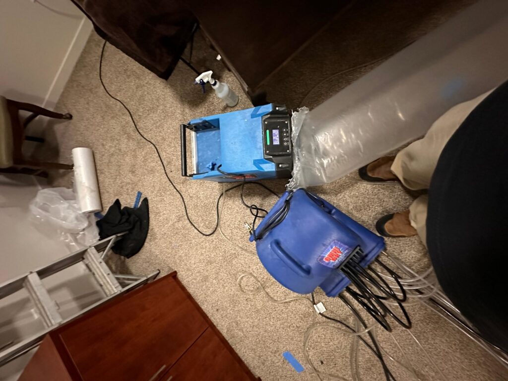 Professional water damage drying equipment, including an air mover and dehumidifier, set up on carpet by The Recover Tech Restoration in Vancouver, WA.