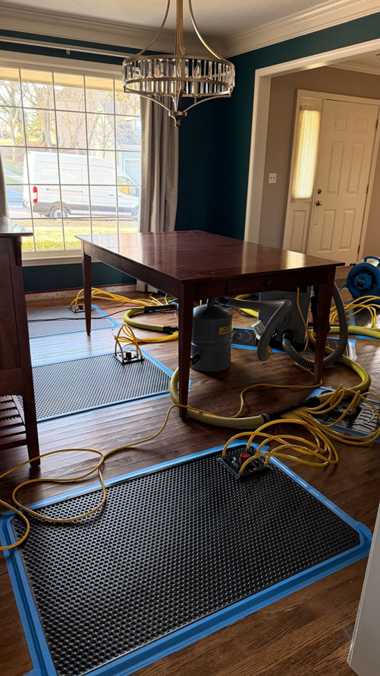 Water damage drying equipment, including air movers and drying mats, set up on a wooden floor by Cowboy Certified Plumbing & Water Cleanup in Lee's Summit, MO.