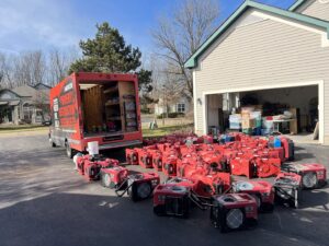 Numerous red air movers and drying equipment lined up on a driveway for water damage restoration by Americon Restoration in Youngstown, OH.