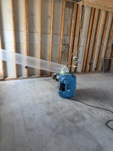 Water damage drying equipment with a plastic duct in a room with exposed studs at a New Method Restoration job in Edison, NJ.