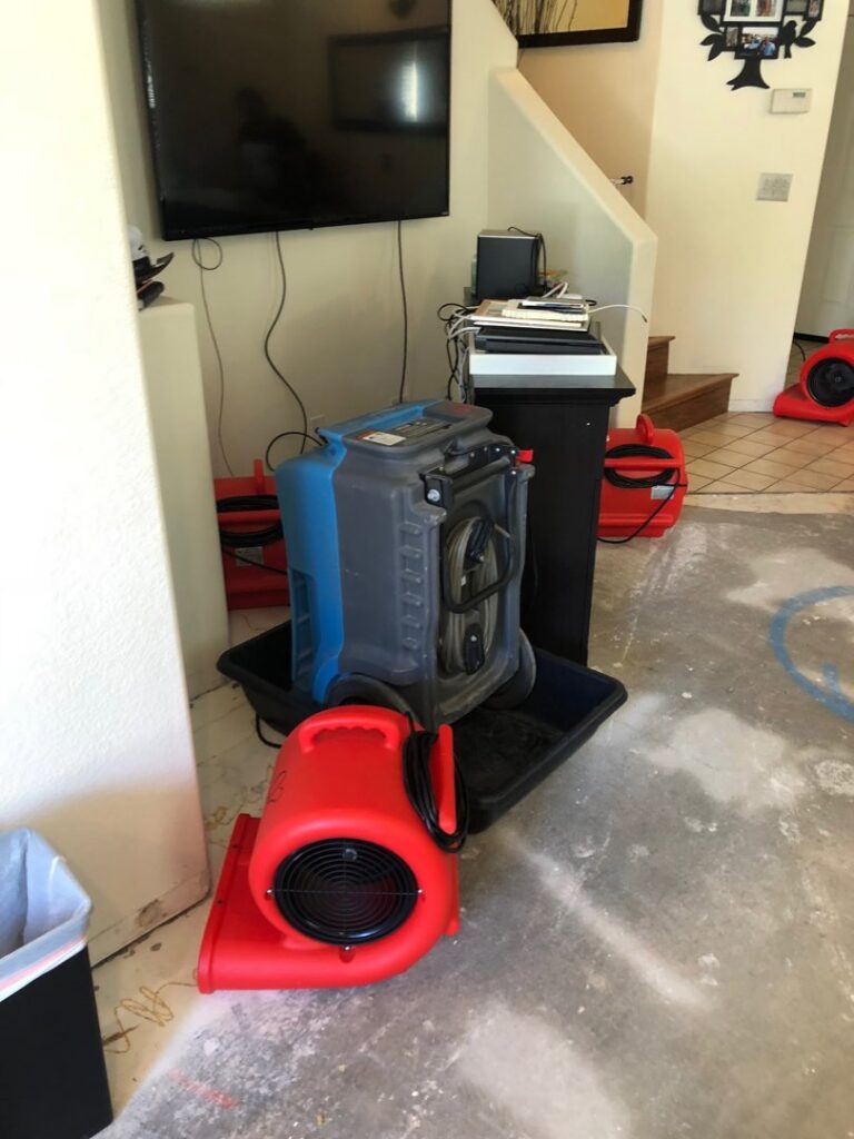 Water damage drying equipment, including air movers and a dehumidifier, in a home by EZ Water Damage Restoration Services, Chula Vista, CA.