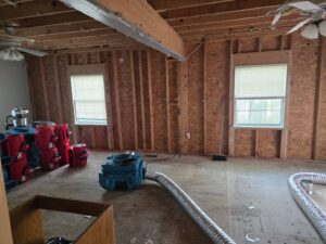 Industrial drying equipment and exposed studs in a room undergoing water damage restoration by GOD'S GLORY LLC in Bowie, MD.