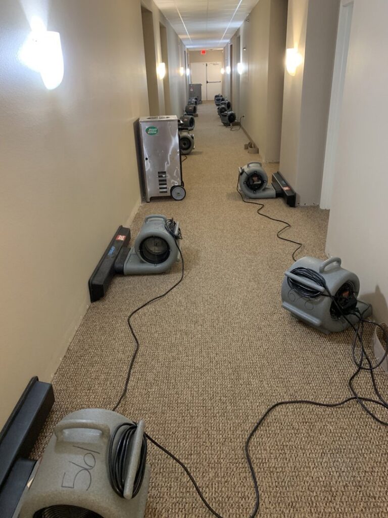A hallway filled with air movers and dehumidifiers for water damage drying by Specialized Cleaning & Restoration, Inc. in Bismarck, ND.