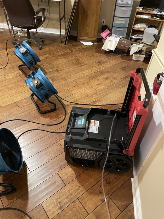 Water damage drying equipment, including air movers and a dehumidifier, on a hardwood floor by Healthy Interior Solutions in Fishers, IN.