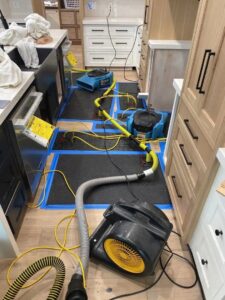 Water damage drying equipment, including air movers and dehumidifiers, set up in a kitchen by Idaho Disaster Pros in Idaho Falls, ID.