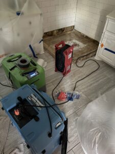 Water damage drying equipment and exposed subfloor in a kitchen, showing remediation by Minutemen Property Damage Services in North Charleston, SC.