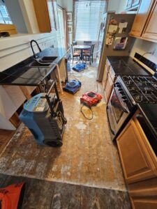 Water Damage, Inc. drying equipment, including air movers and dehumidifiers, in a kitchen restoration in Denver, CO.