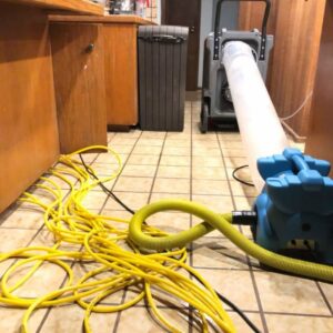 Water damage drying equipment, including an air mover and dehumidifier, set up in a kitchen by Rescue One Restoration in Honolulu, HI.