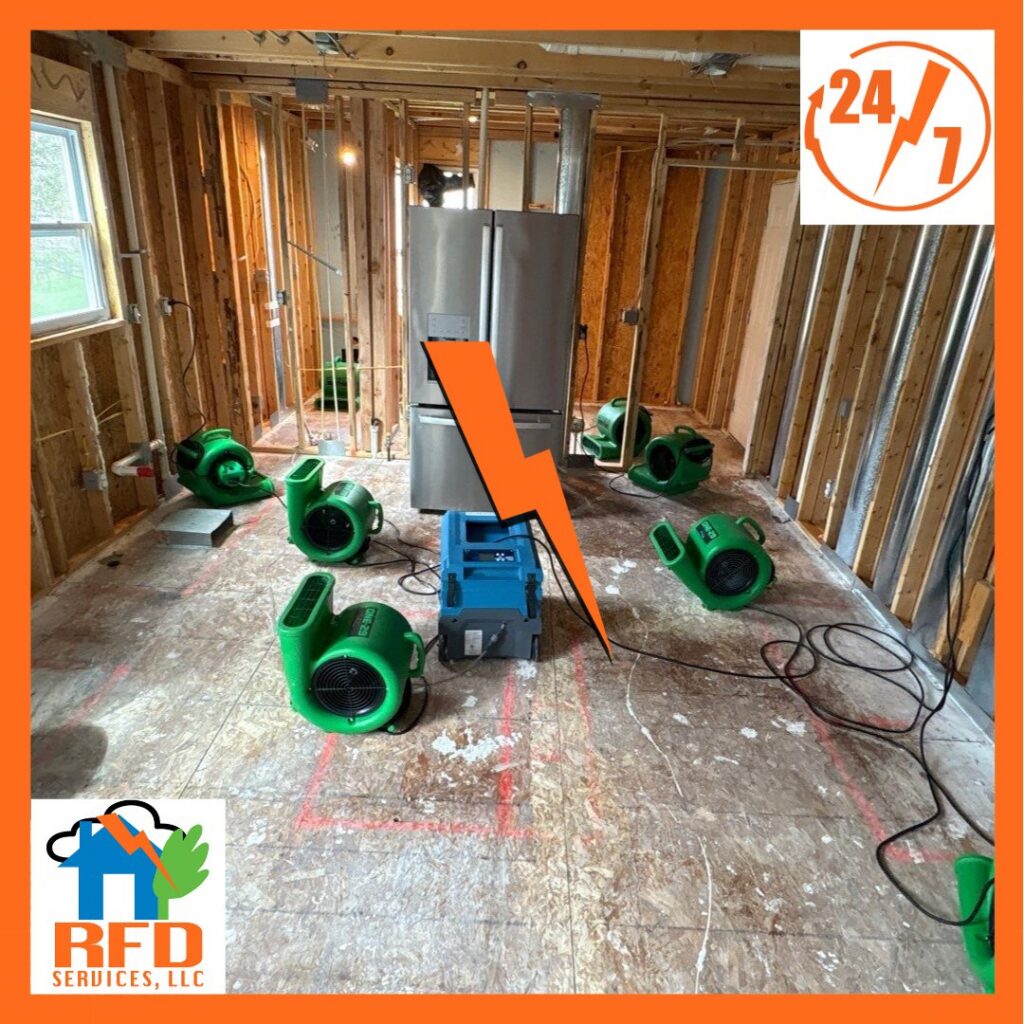 Water damage drying equipment, including air movers and a dehumidifier, in a kitchen with exposed studs by RFD Services in Akron, OH.