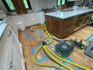 Specialized drying equipment and hoses on a kitchen floor for water damage restoration by Servpro Toledo East in Toledo, OH.