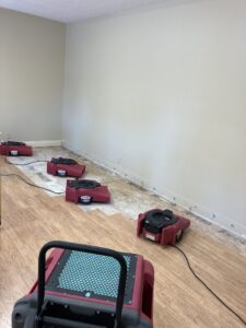 Multiple air movers drying a wooden floor after water damage restoration by PuroClean of Tuscaloosa in Northport, AL.
