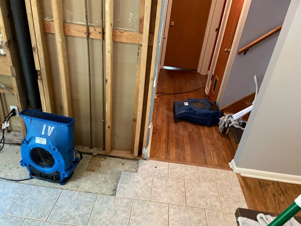 Water damage drying equipment, including air movers and a dehumidifier, in a room with exposed studs by Sentry Restoration in Volo, IL