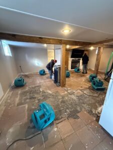 Water damage specialists setting up air movers and dehumidifiers for drying a damaged room at a client's property by H2O Pros Water Restoration Services in Westland, MI.