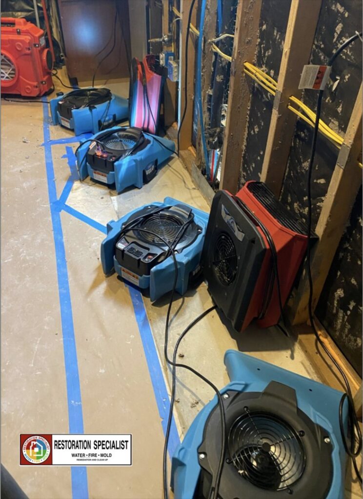 Multiple air movers and drying equipment set up in a room for water damage restoration by Restoration Specialist in O Fallon, MO.