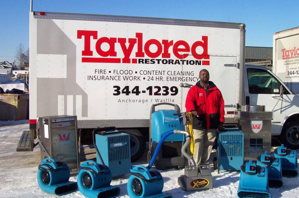 A Taylored Restoration specialist with water damage drying equipment in front of a company truck in Anchorage, AK