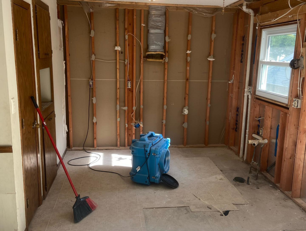 A blue industrial fan drying a room with exposed studs after water damage by Viking Restoration Services in Rochester, MN.