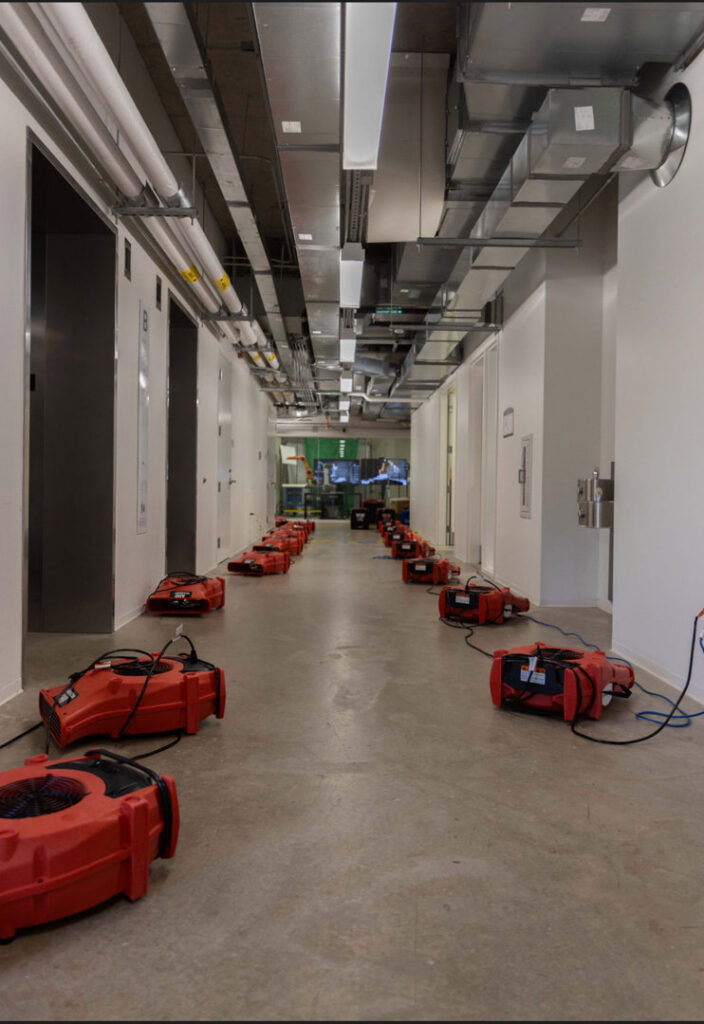 A long hallway with numerous red air movers and drying equipment for water damage restoration by Americon Restoration in Youngstown, OH.