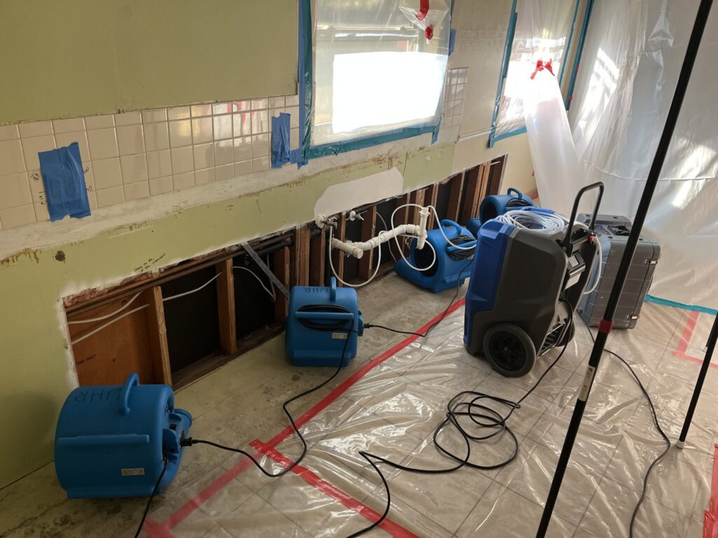 A water damage drying setup with air movers and exposed walls in a kitchen area by Utah Home Restoration in Springville, UT