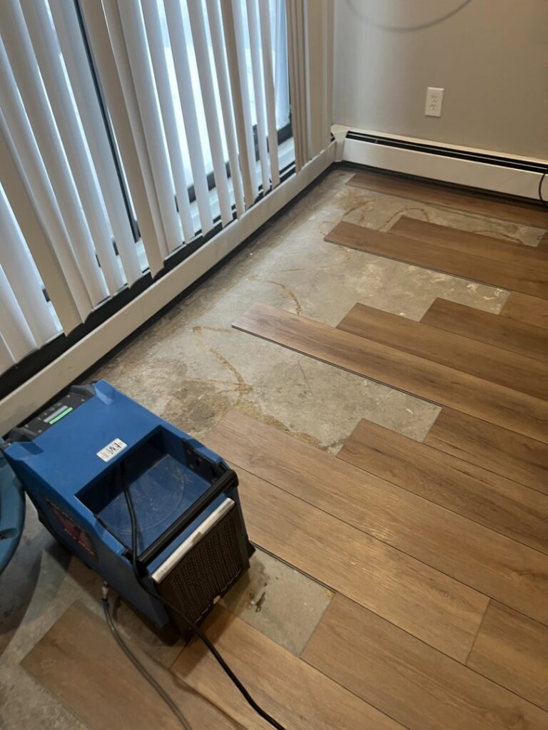 Water damaged flooring removed with a dehumidifier running during restoration by Restoration Network Inc in Osseo, MN.