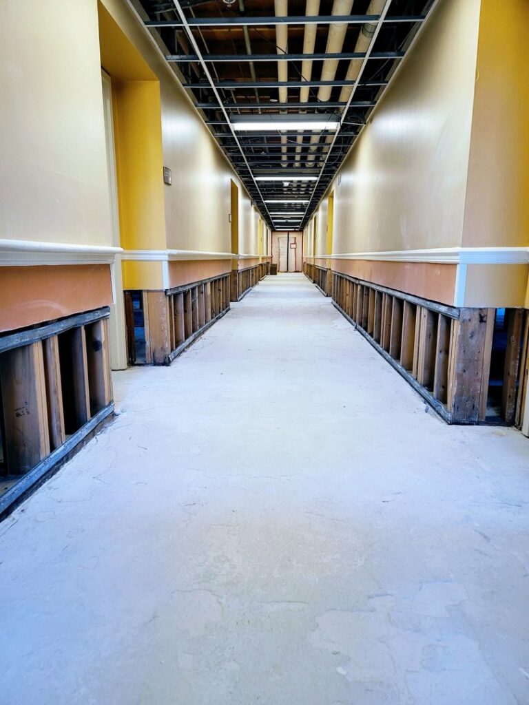 A hallway with drywall removed due to water damage, showing exposed studs by Pure Restore in Northglenn, CO.