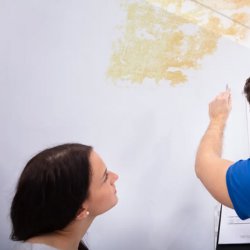 A RestoPros technician inspecting water damage and stains on a ceiling in Norfolk County, MA.