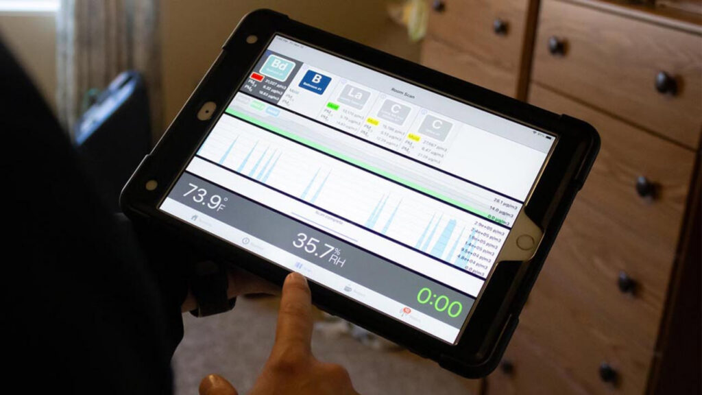 A Pure Restore technician monitoring environmental readings on a tablet during water damage restoration in Northglenn, CO.
