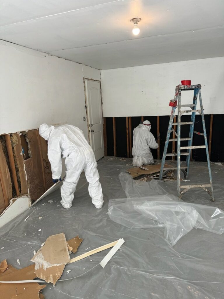 A water damage remediation crew in hazmat suits removing damaged drywall at a job site for RestoPros of Hartford in West Hartford, CT.