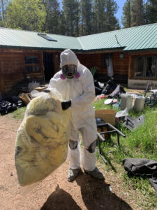 A Property Doctors, Inc. specialist in Denver, CO, removing water-damaged debris from a home in a hazmat suit.