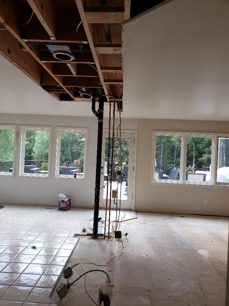 A room undergoing water damage remediation with ceiling and floor removed, exposing pipes at Roy Briley General Contracting in Anchorage, AK.