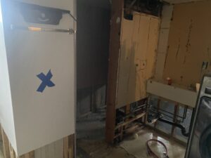 An interior room undergoing water damage remediation with exposed pipes and wet floor at ServiceMaster of Salt Lake in Salt Lake City, UT