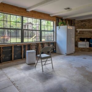 A room with walls removed and a dehumidifier, showing water damage remediation by Built Different Restoration in Gilbert, AZ.